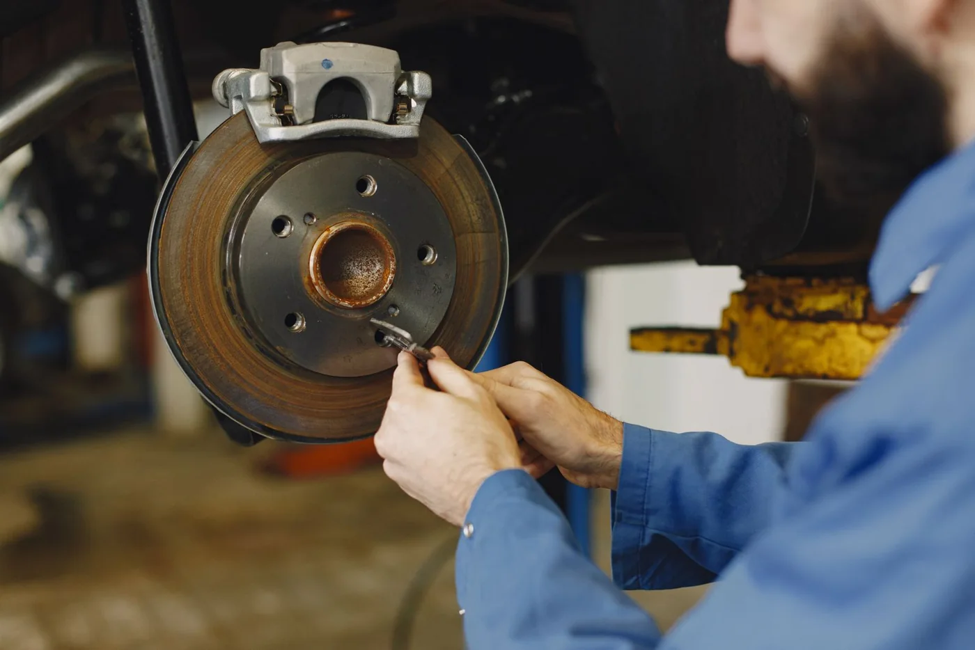 Mechaniker prüft Bremsen eines Fahrzeugs in einer Werkstatt, illustratives Stockfoto